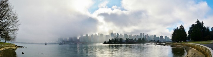 Panoramic view of Downtown Vancouver from Stanley Park.With a slight break of clouds and fog this panoramic view of Downtown Vancouver reveals its beautiful skyline as seen from Stanley Park.
